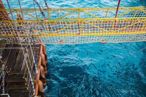 View of an offshore crew walking at the gangway to offshore drilling rig with life life buoys