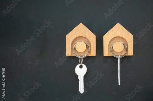Wooden key hanger against black wall background.