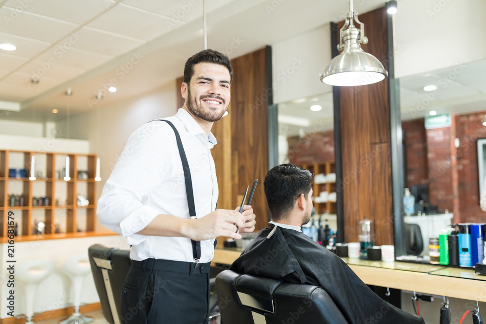 Stylist Smiling While Grooming Client's Hair In Barber Shop