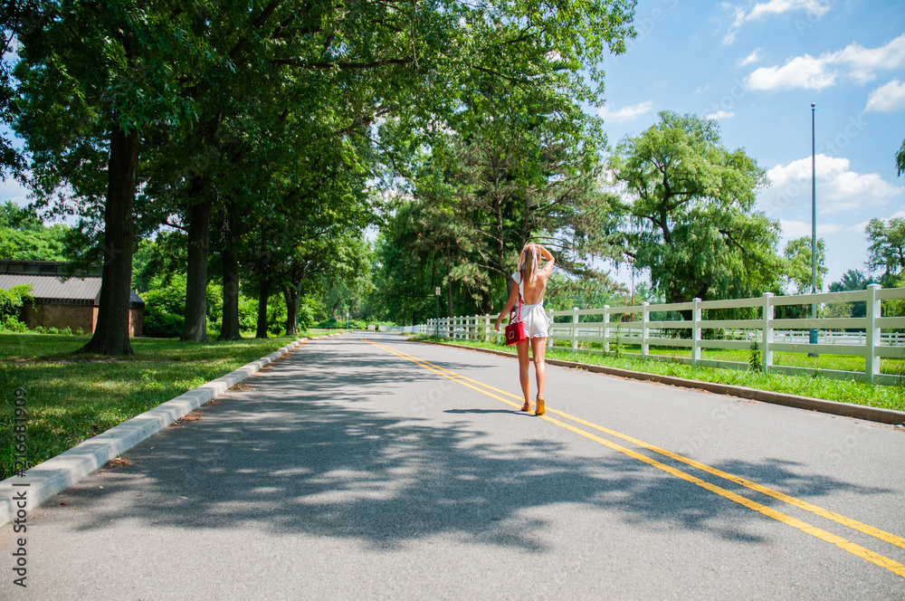 Beautiful fashionable woman walking on the road in summer