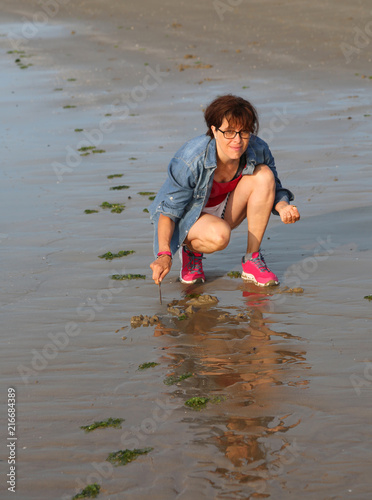 woman collects shells and clams on the beach during low tide