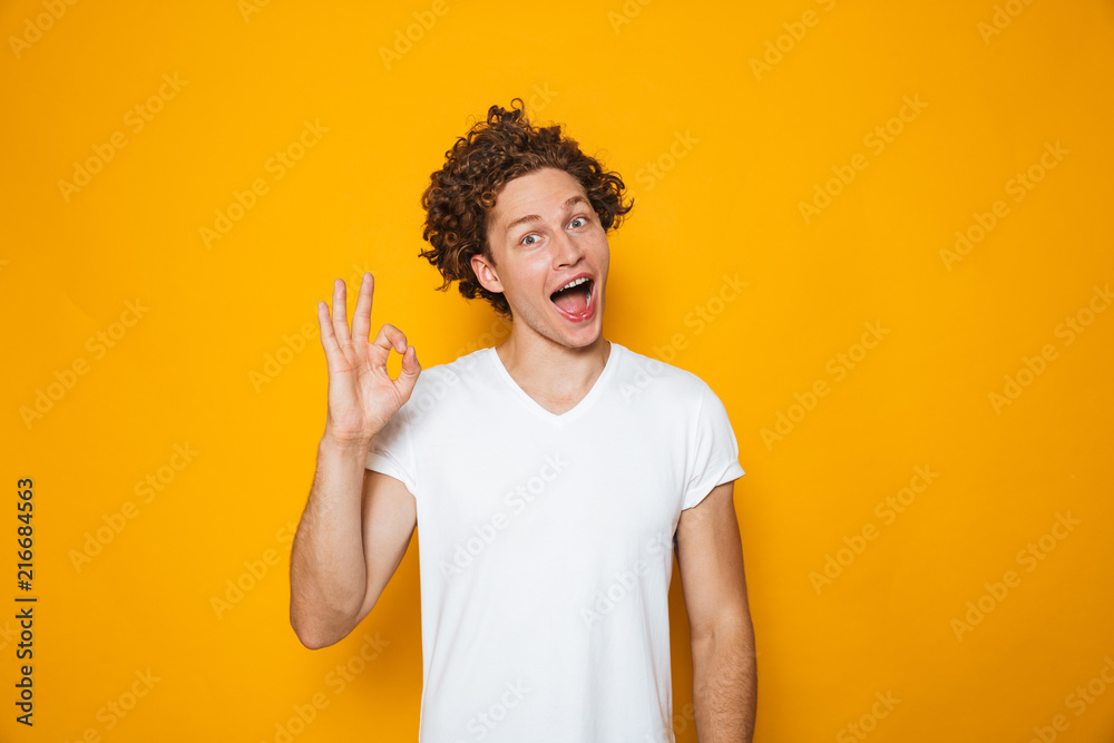 Portrait of a smiling curly haired man showing ok Portrait of a smiling curly haired man showing ok