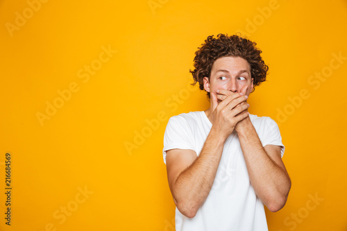 Portrait of a shocked curly haired man covering mouth © Drobot Dean