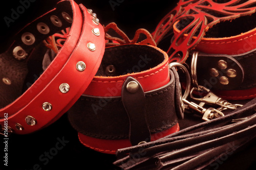 Leather whip, red leather handcuffs, red mask on a black background