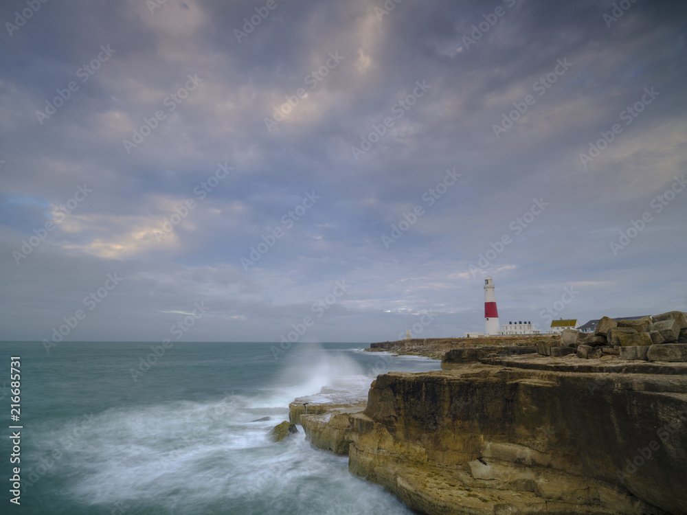 Summer sunrise with stormy clouds and slow shutter speed at Portland Bill Light, Dorset, UK
