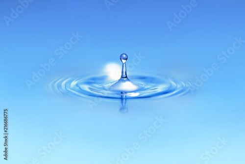 Closeup on drop of water falling in a blue liquid.