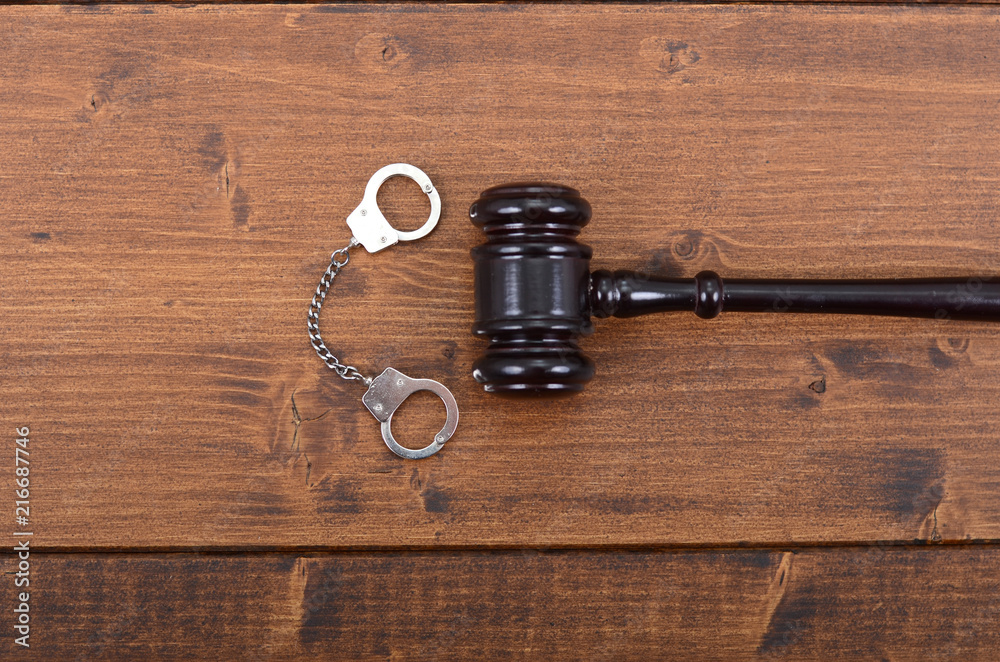 Judge Gavel and Handcuffs on a black wooden background. Judge Gavel and Handcuffs on a black wooden background.