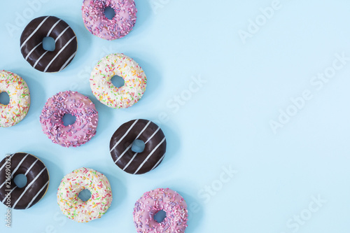 Flat lay donuts pattern on a pastel blue background with copy space for slogan.