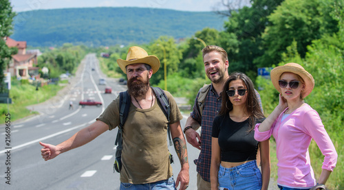 Friends hitchhikers travelling summer sunny day. Begin great adventure in your life with hitchhiking. Company friends travelers hitchhiking at edge road nature background. Travellers try to stop car