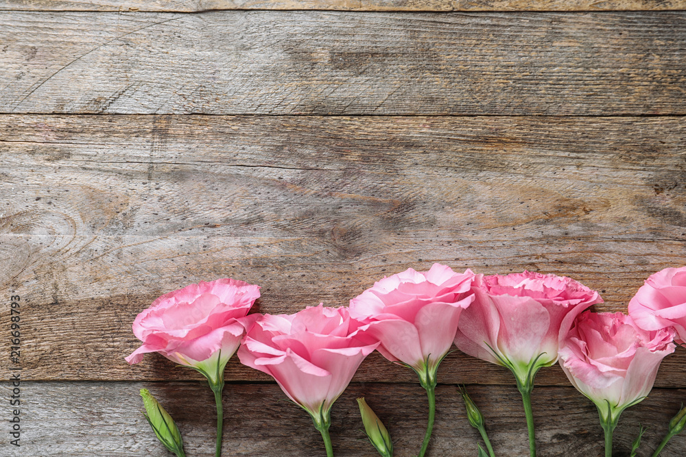 Flat lay composition with beautiful Eustoma flowers on wooden background