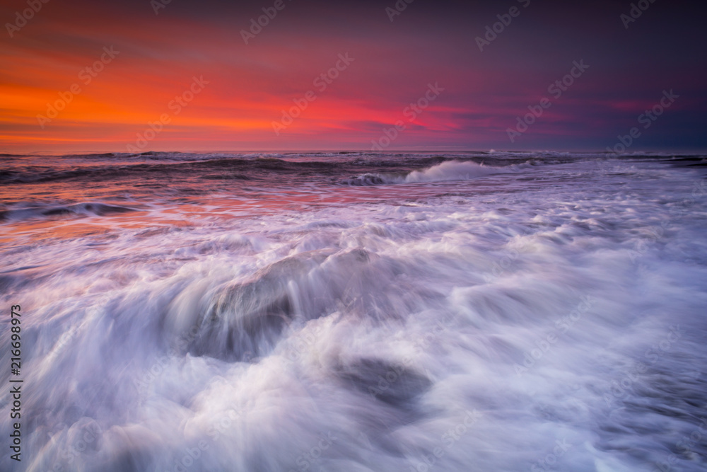 Obraz premium Jokulsarlon beach at sunrise, long exposure photography with waves and pieces of ice on the black sand beach.