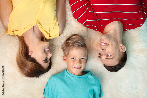 Little boy with mother and father lying on fuzzy rug, top view