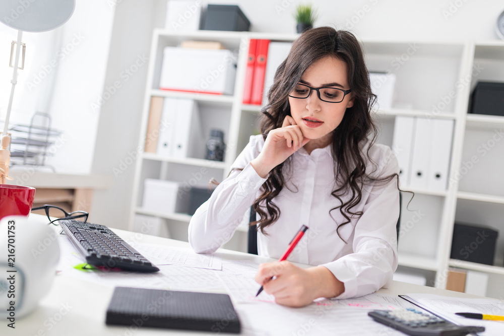 Young girl sits at office desk and fills documents with her left hand. Young girl sits at office desk and fills documents with her left hand.
