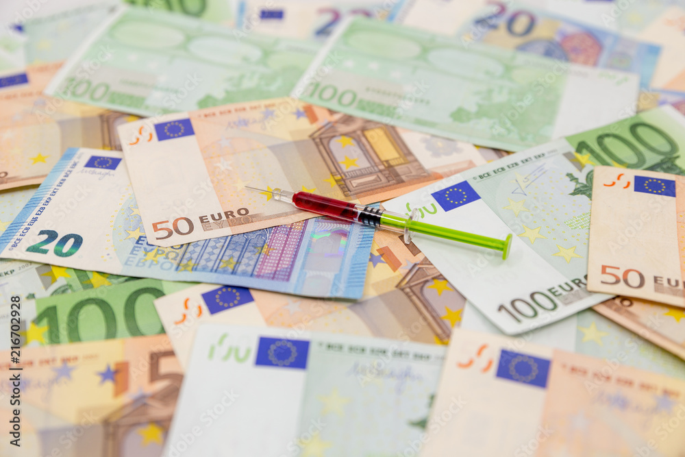 Spread Stack of Euro Banknotes with syringe on top of them, health costs concept Spread Stack of Euro Banknotes with syringe on top of them, health costs concept
