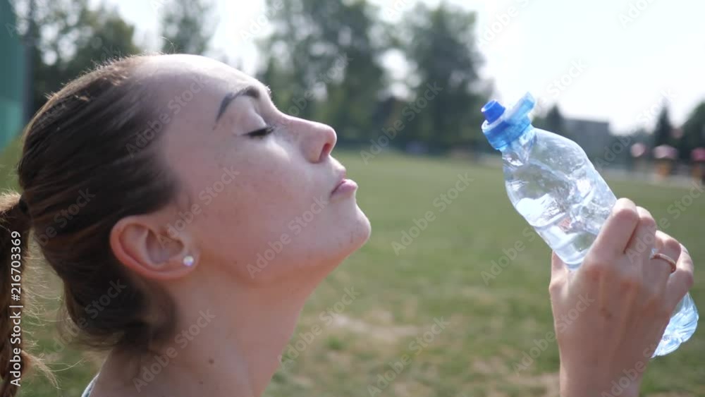 Sport training young woman portrait drinking a bottle of clean pure water during workout outdoors Sport training young woman portrait drinking a bottle of clean pure water during workout outdoors