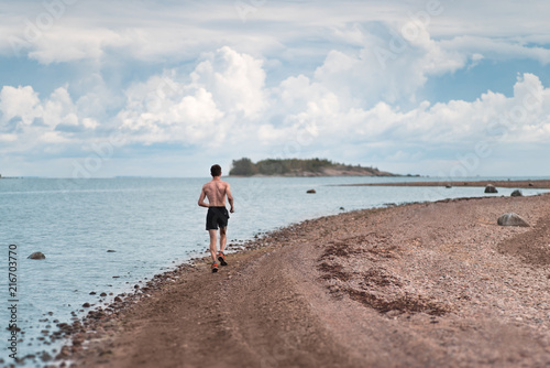 A man runs along the shore. A picturesque place.
