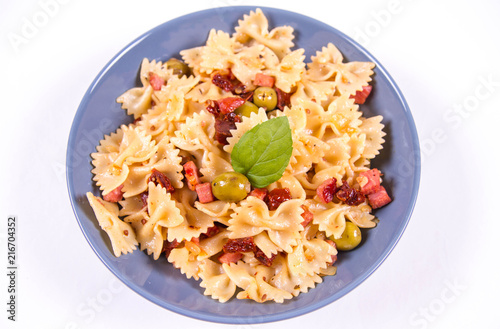 Farfalle pasta with sun dried tomato, ham and olives decorated with fresh mint