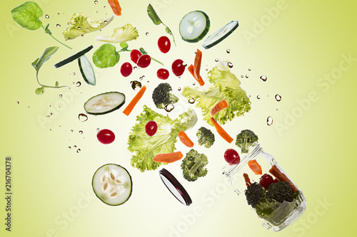 Salad in the pot with all ingredients floating out of the pot on green gradient background and splashing water