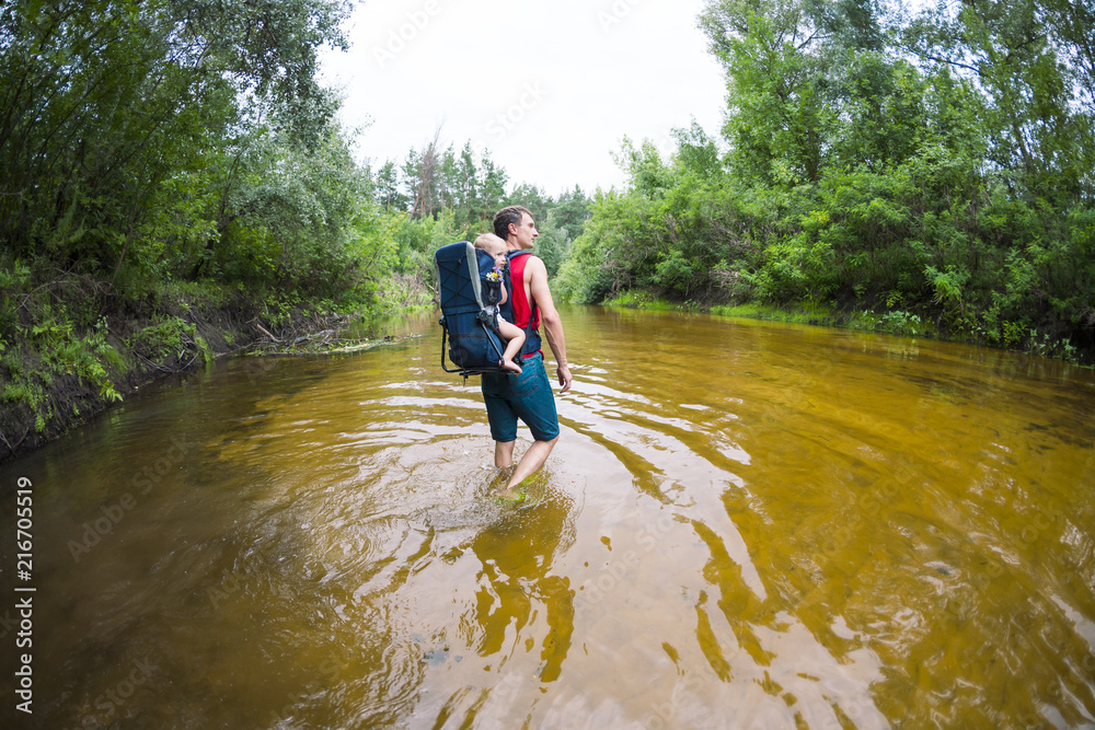 A man with a child crosses the river ford. A man with a child crosses the river ford.