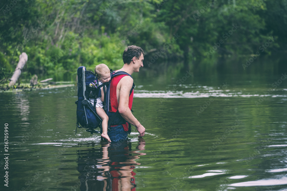 A man with a child crosses the river ford. A man with a child crosses the river ford.