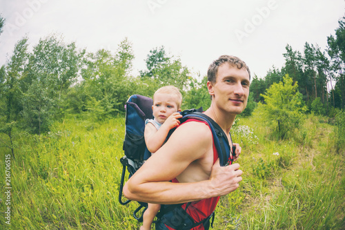 A man carries a child in a backpack.