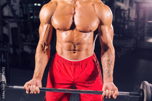 Close up of muscular young man lifting weights in gym