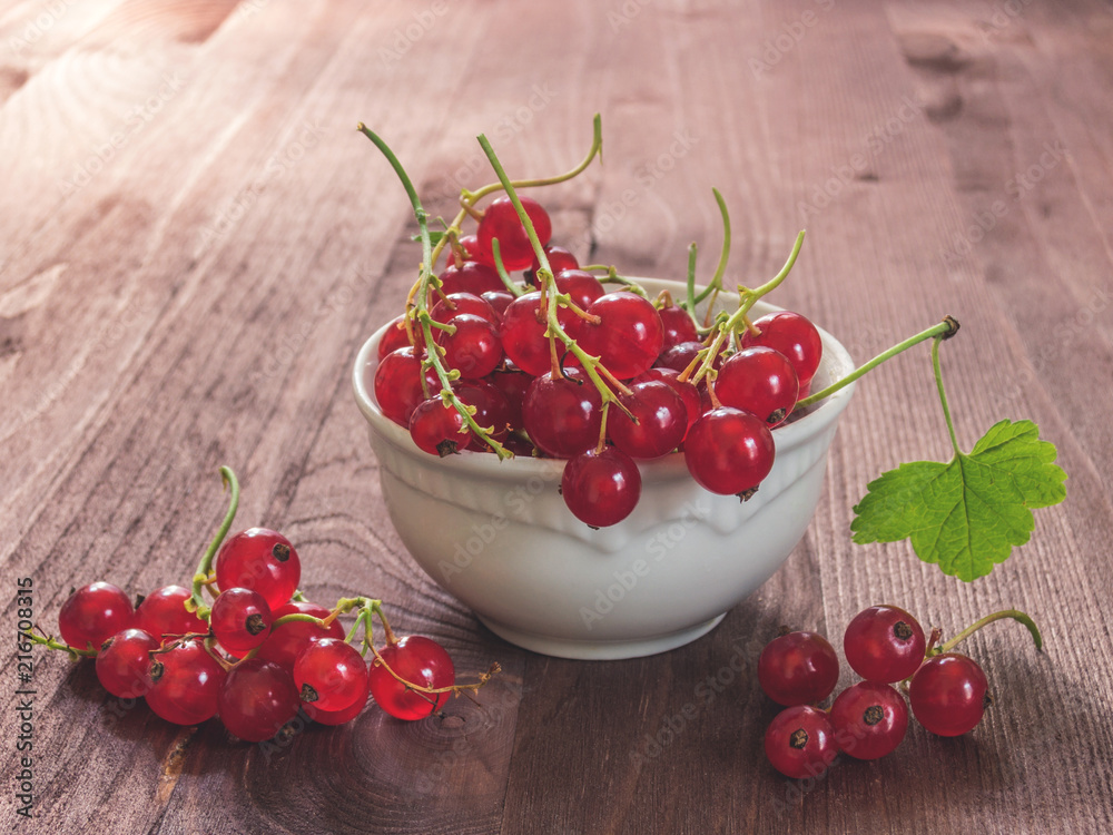 Fresh red currant in white ceramic plate on wood background Fresh red currant in white ceramic plate on wood background
