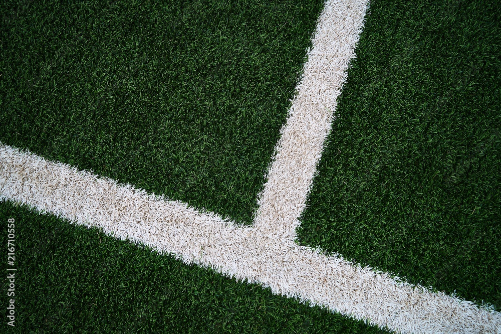 Fototapeta premium Artificial green grass football / soccer field / pitch & white stripe - close up