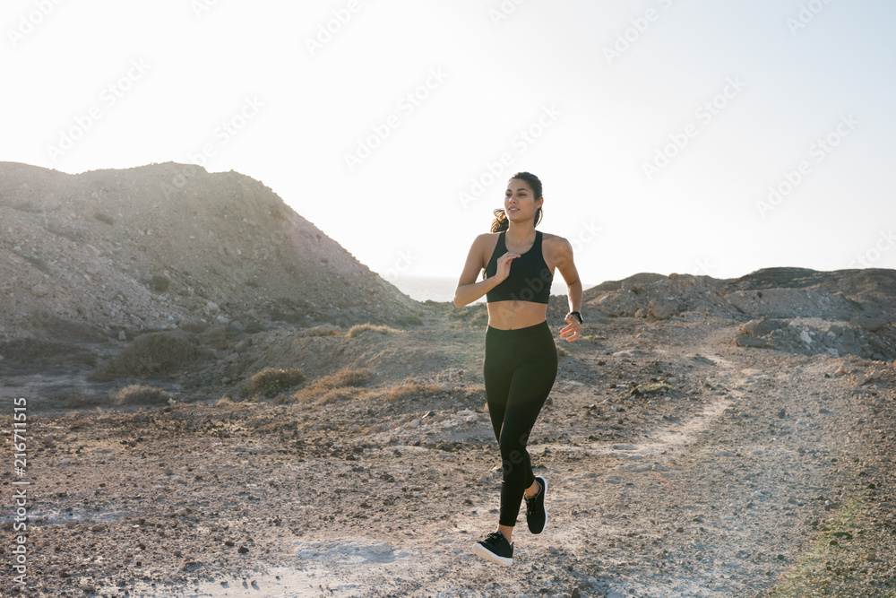 Young woman running along a dusty path in desert