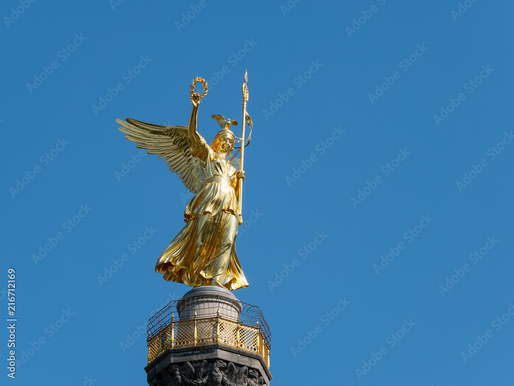 Fototapeta premium The Golden Statue of Victoria On Top of The Victory Column in Berlin, Germany Against A Blue Sky