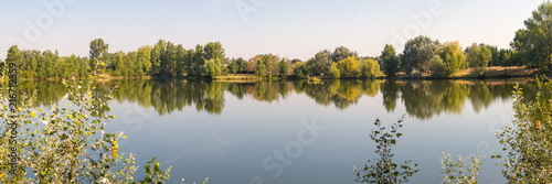 Lac de Lamartine, reflet des arbres sur l'eau. Vue sur le lac durant une journée d'été.Roques, Frouzins, France