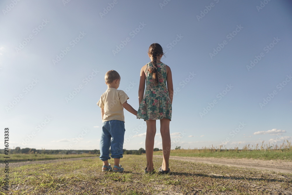 small boy and girl standing on a rural road