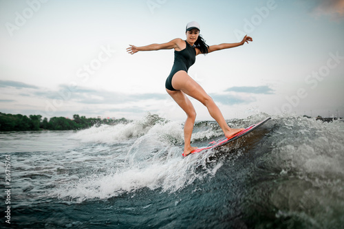 Rear view young active girl riding on the wakesurf