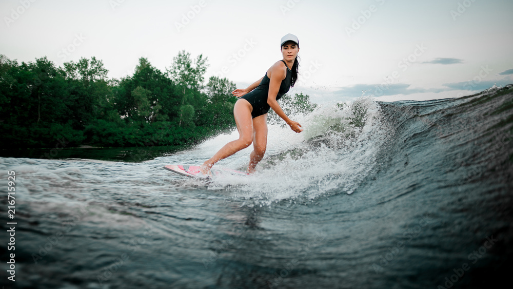 Young attractive woman riding on the wakesurf