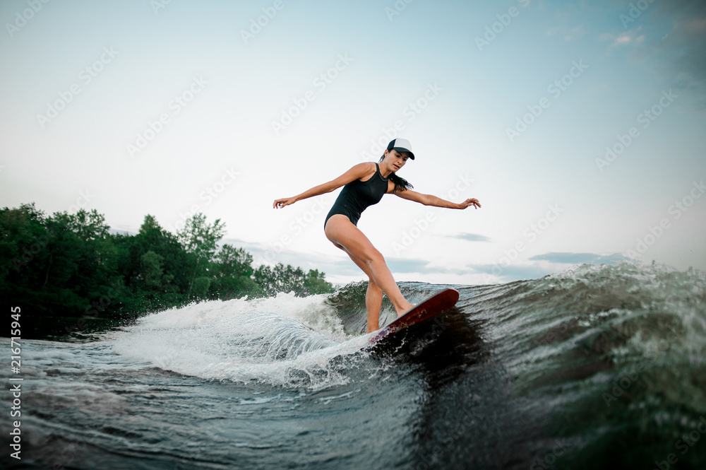 Young attractive woman riding on the orange wakesurf