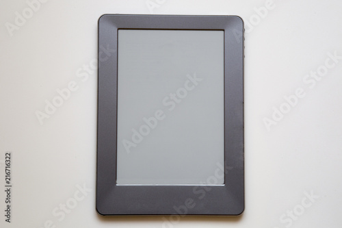 E-book reader device on desk in library. Alternative for traditional books