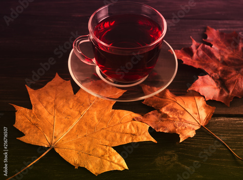 ?up with red Chinese tea on maple leaves on a wooden table