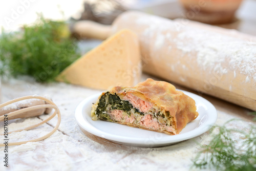 strudel with fish and spinach on a wooden board with flour