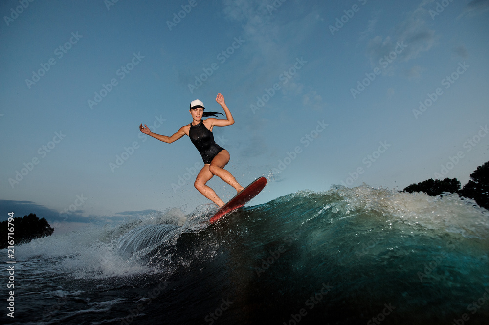 Young amazing woman riding on the orange wakesurf