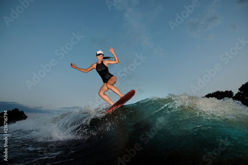 Young amazing woman riding on the orange wakesurf