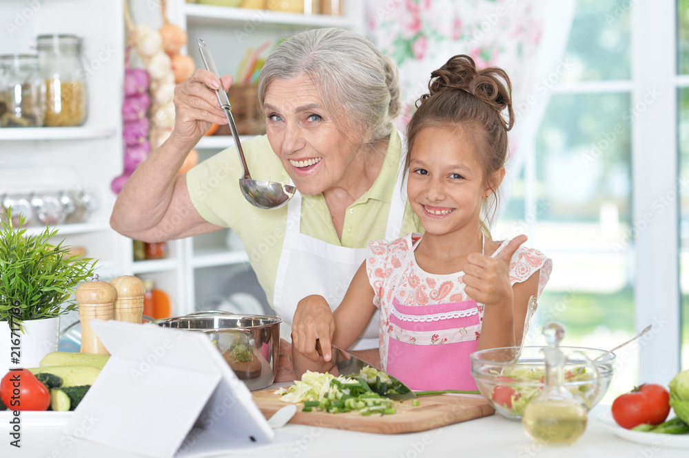 grandmother and granddaughter preparing dinner 