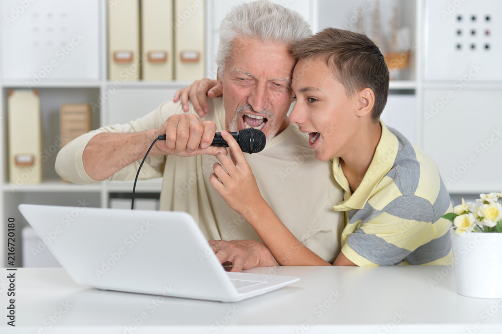 boy and grandfather singing karaoke with with a laptop boy and grandfather singing karaoke with with a laptop