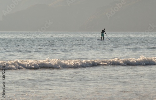 Homme sur une planche à rame en bord de mer © graphlight
