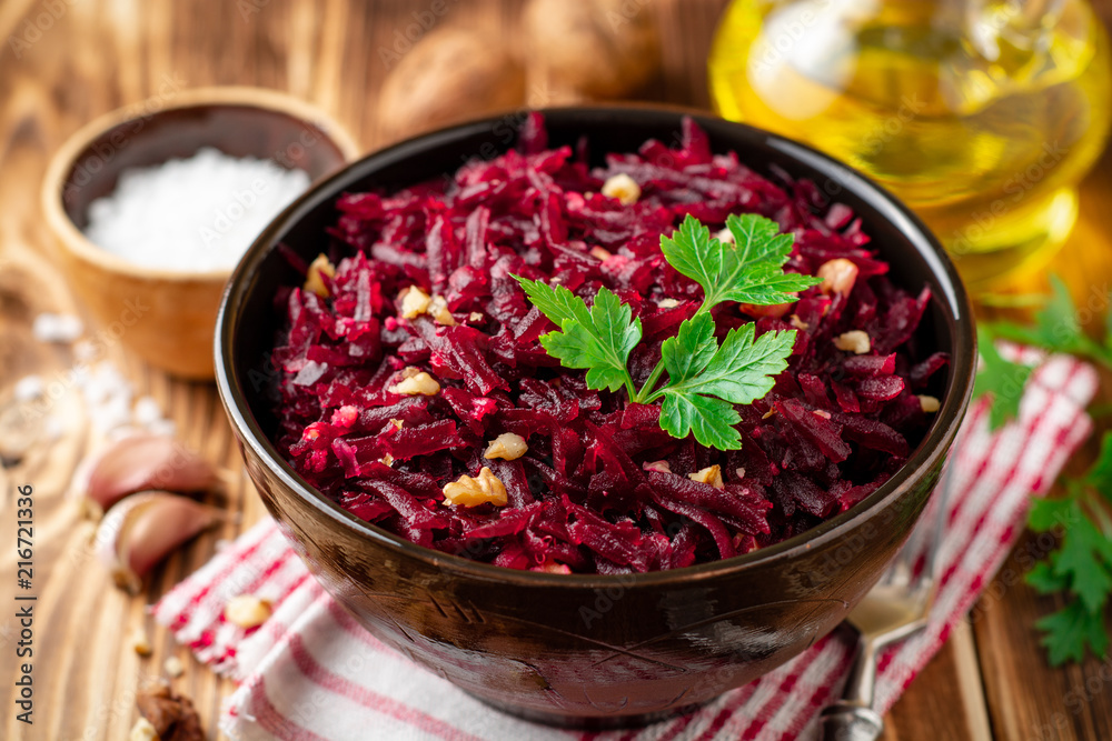 Beetroot salad with wallnuts and garlic in bowl on wooden table Beetroot salad with wallnuts and garlic in bowl on wooden table