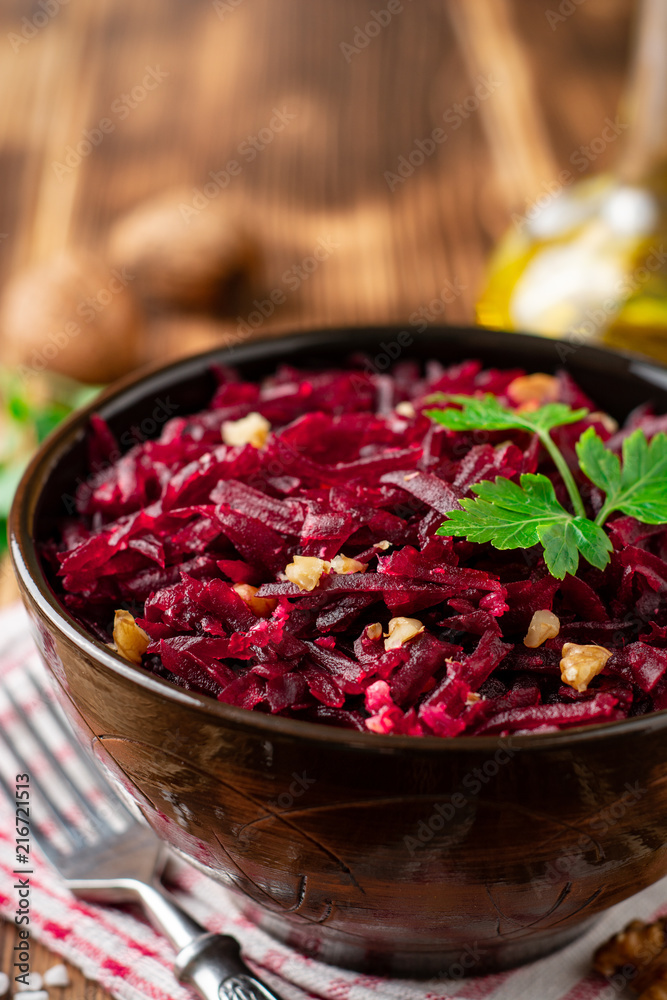 Beetroot salad with wallnuts and garlic in bowl on wooden table Beetroot salad with wallnuts and garlic in bowl on wooden table