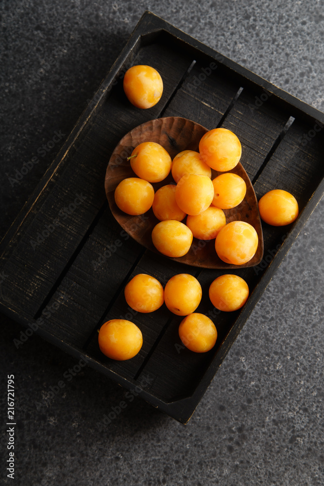 Sweet summer yellow plums on wooden tray. Top view