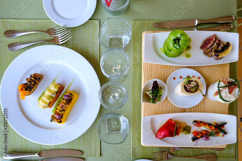 Table servi avec le plateau de petits plats: poivron farci, filet de sardines, crevettes, fromage de chevre, tartare de taureau, tomate verte farci, carpaccio d'agneau. et des moules.
