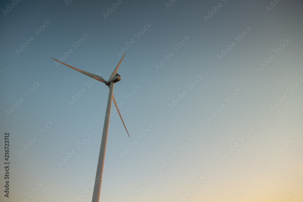 Wind mill on a field during warm sunrise light. Summer day. Green eco friendly energy source. Copy space Wind mill on a field during warm sunrise light. Summer day. Green eco friendly energy source. Copy space