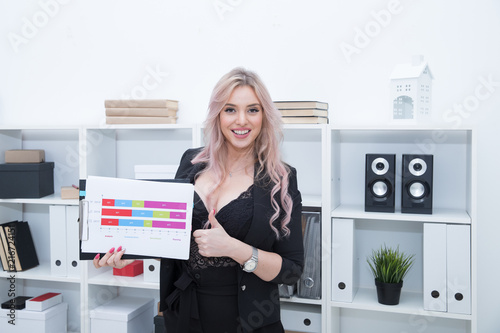 A beautiful girl smiles and holds the company's development schedule in her hands