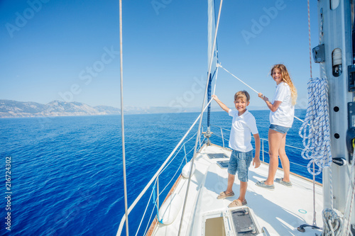 Boy with his sister on board of sailing yacht on summer cruise. © Max Topchii
